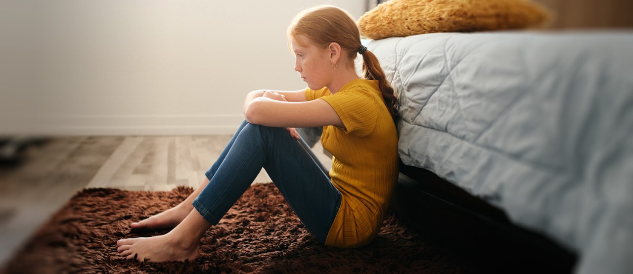  Girl upset and thoughtful sitting on floor in her bedroom. 