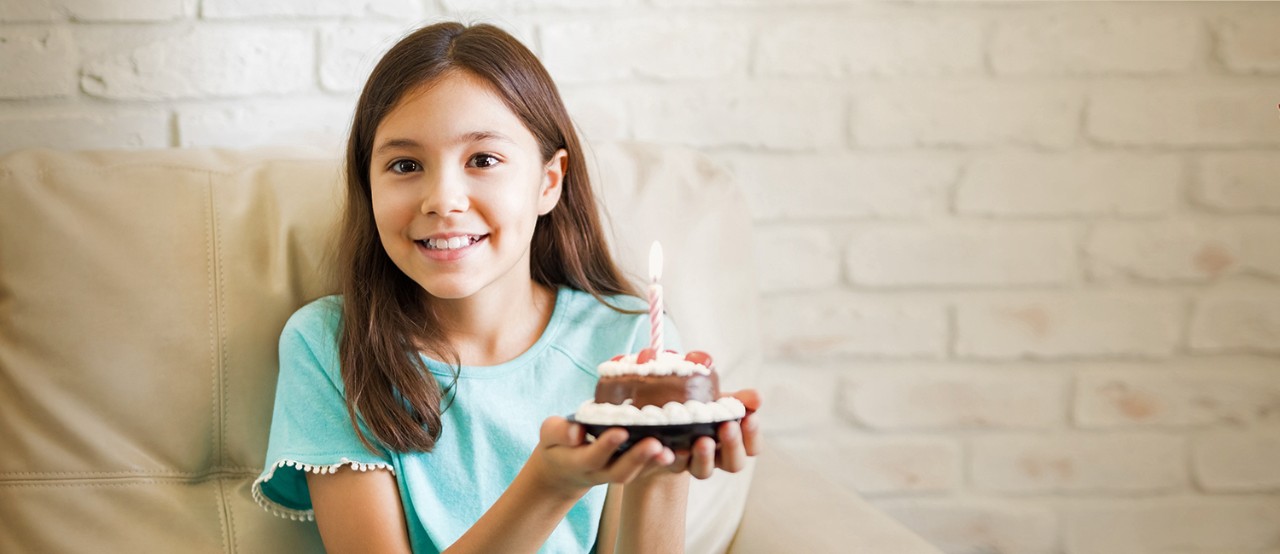  Una niña feliz sosteniendo su pastel de cumpleaños en sus manos. 